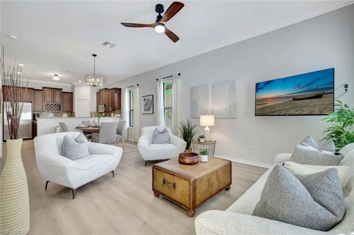 Living room featuring light wood finished floors, a chandelier, crown molding, and a ceiling fan