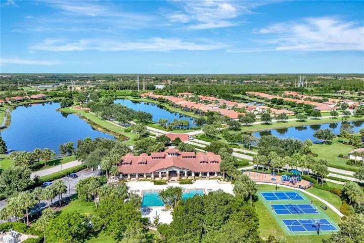 Aerial perspective of suburban area featuring a nearby body of water and a tree filled landscape