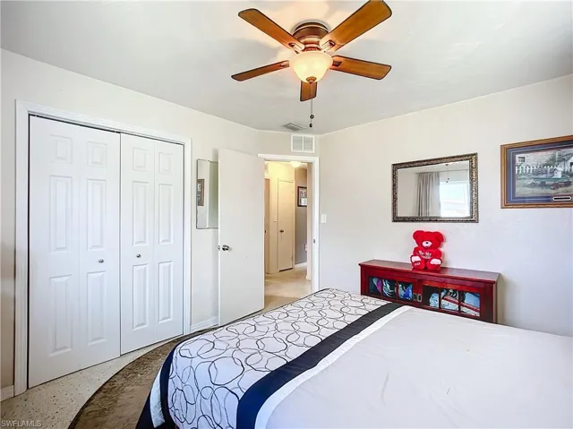 Bedroom featuring light speckled floor, a closet, visible vents, and a ceiling fan