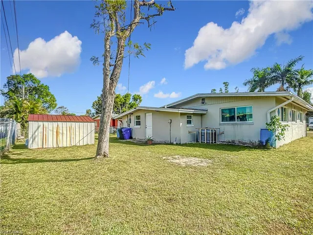 Back of property with a yard, a shed, fence, and an outdoor structure