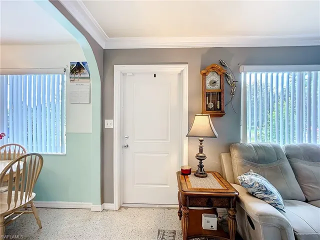 Entryway with baseboards, arched walkways, crown molding, and speckled floor