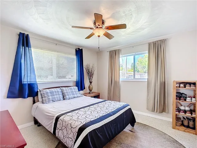 Bedroom featuring ceiling fan, speckled floor, and baseboards