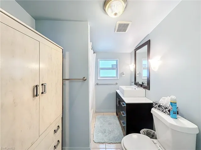 Bathroom featuring toilet, vanity, tile patterned flooring, and visible vents