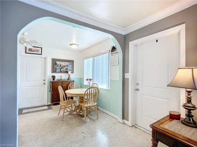 Dining room with ceiling fan, arched walkways, baseboards, and ornamental molding