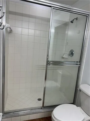 Bathroom featuring a shower with shower door and toilet
