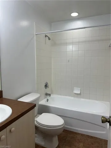 Full bathroom with toilet, tile patterned floors, vanity, and tiled shower / bath