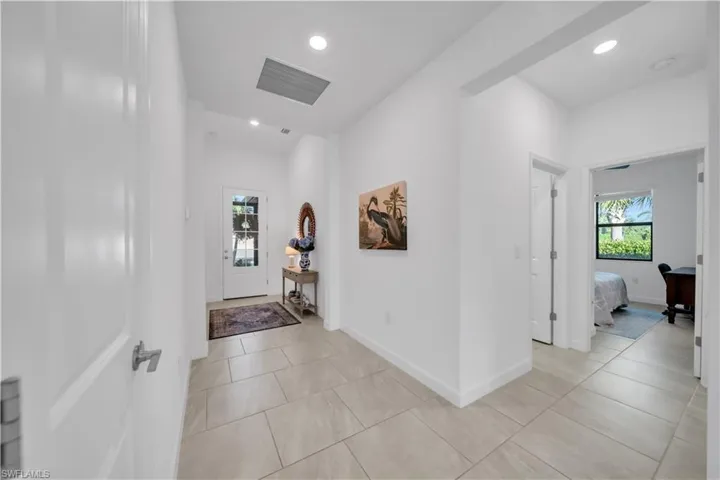 Hall featuring recessed lighting, healthy amount of natural light, light tile patterned floors, and an office area