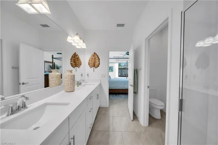 Bathroom featuring ensuite bath, double vanity, ceiling fan, light tile patterned flooring, and a shower stall