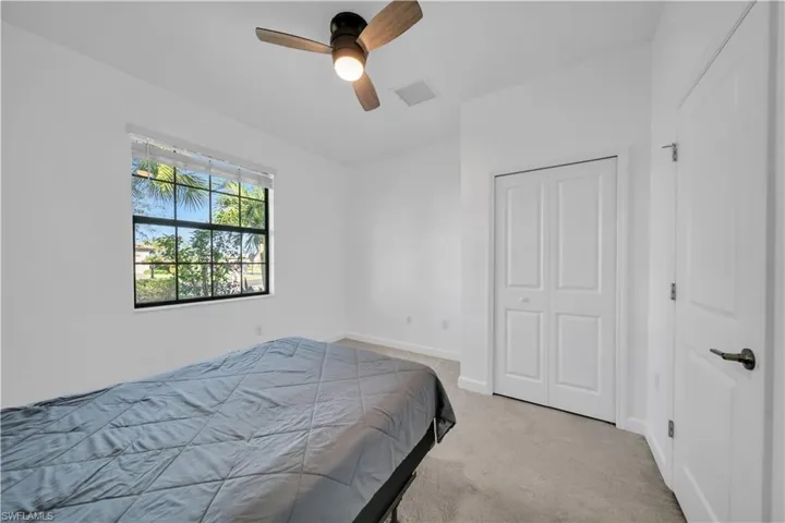 Bedroom 4 with light carpet, ceiling fan, and a closet