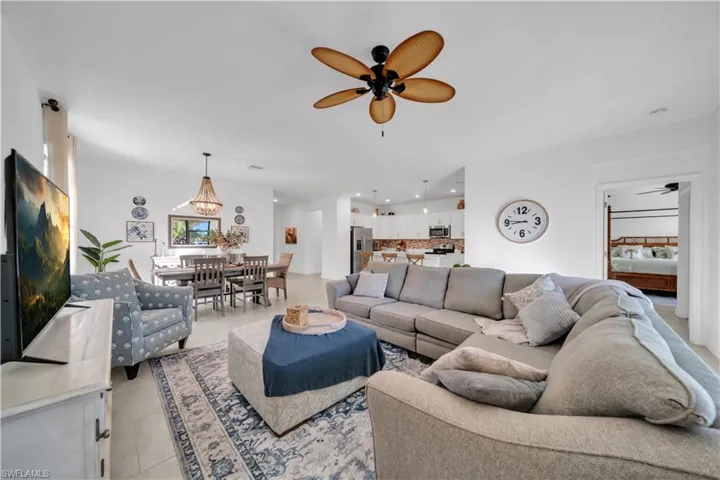 Living room with ceiling fan, light tile patterned flooring, and recessed lighting