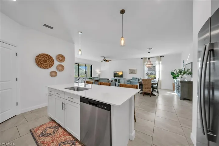 Kitchen with appliances with stainless steel finishes, a ceiling fan, a center island with sink, white cabinetry, and light tile patterned floors