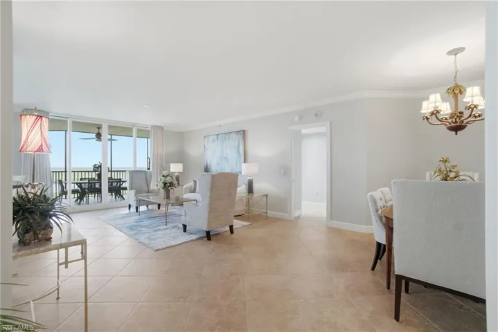 Living area with floor to ceiling windows, crown molding, a chandelier, light tile patterned floors, and ceiling fan