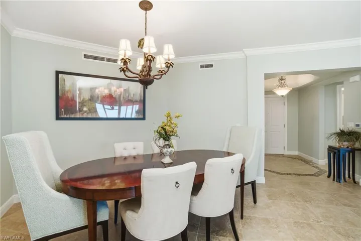 Dining space with crown molding, a chandelier, and light tile patterned floors
