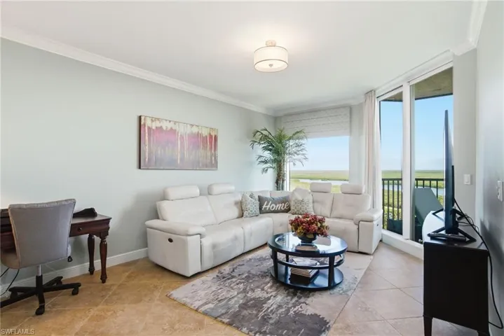 Living room with crown molding, an office area, light tile patterned flooring, and expansive windows
