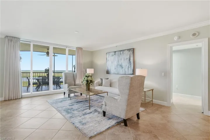 Living area with expansive windows, ornamental molding, and light tile patterned flooring