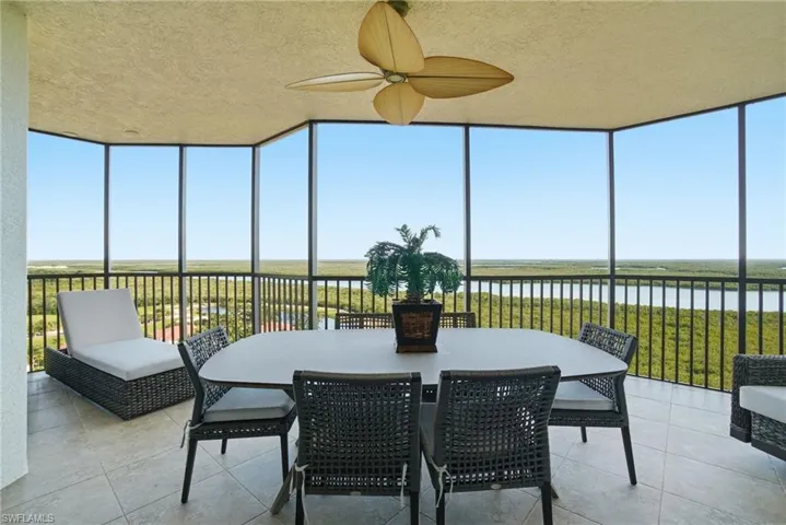 Sunroom featuring expansive windows, a water view, and a textured ceiling