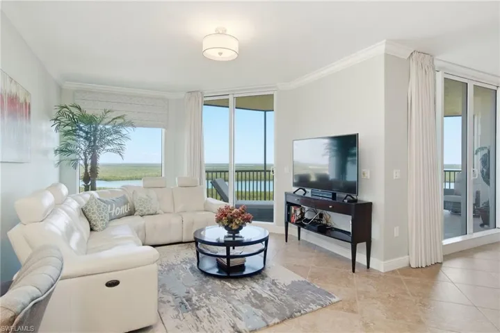 Living room featuring a wall of windows, crown molding, and light tile patterned floors