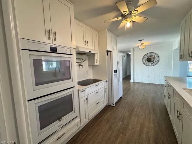 Unfurnished dining area featuring baseboards, dark wood-style floors, a notable chandelier, and plenty of natural light