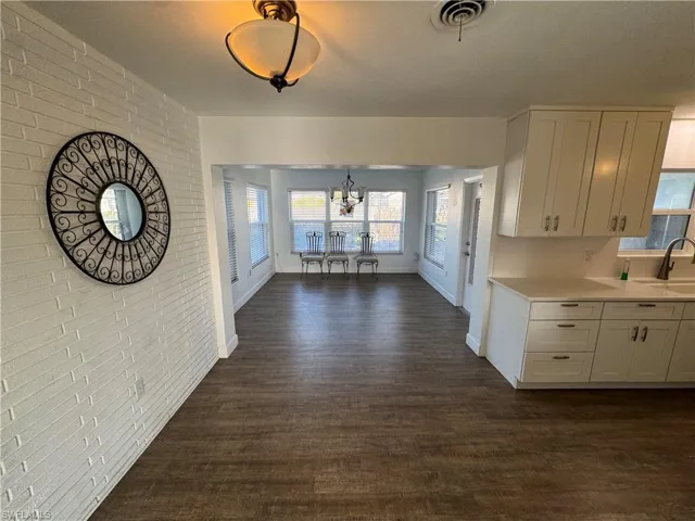 Unfurnished dining area with dark wood finished floors, baseboards, and a notable chandelier
