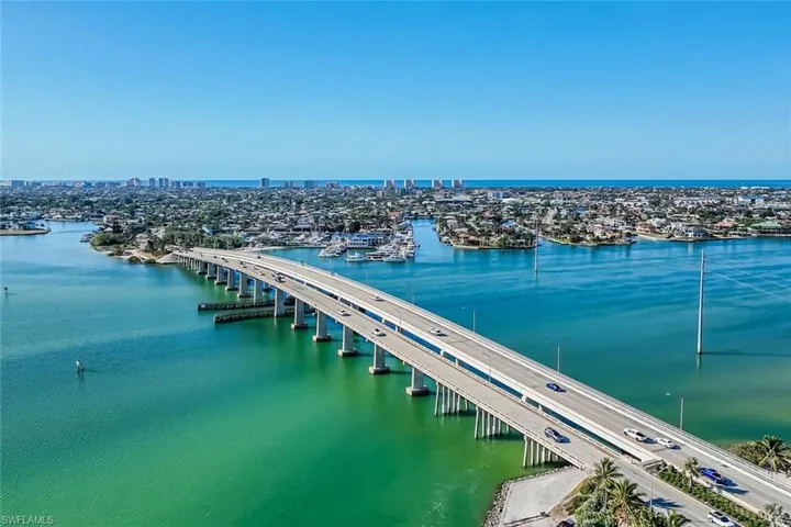 Coastal cityscape with expansive water access, a bustling marina, and a prominent bridge structure