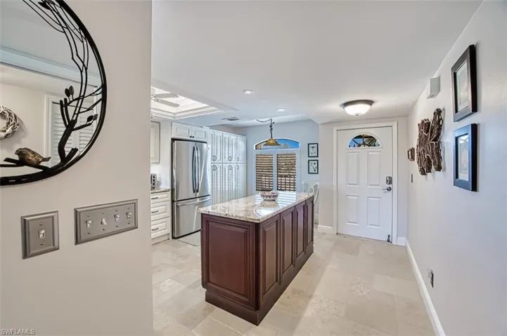 Kitchen featuring light stone counters, dark brown cabinets, stainless steel refrigerator, and a center island