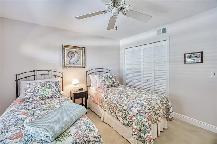 Carpeted bedroom with ceiling fan and a closet