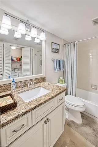 Full bathroom featuring vanity, shower / tub combo with curtain, washing machine and clothes dryer, and toilet