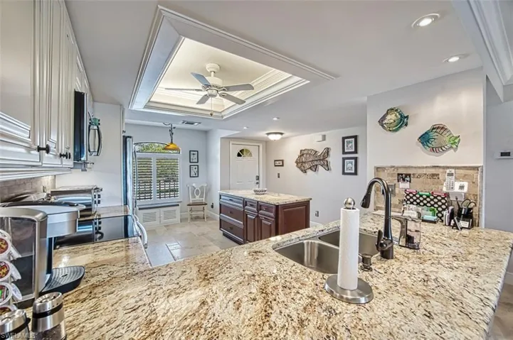Kitchen featuring sink, white cabinets, decorative backsplash, dark brown cabinetry, and a tray ceiling