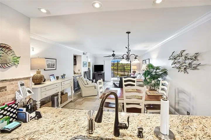 Dining space featuring sink, crown molding, and ceiling fan with notable chandelier
