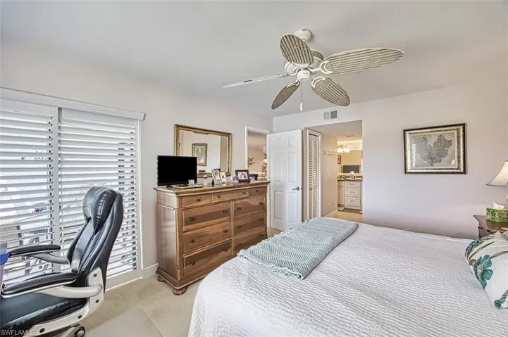 Carpeted bedroom with ensuite bathroom and ceiling fan