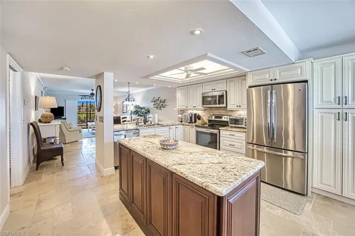 Kitchen featuring backsplash, white cabinets, ceiling fan, kitchen peninsula, and stainless steel appliances