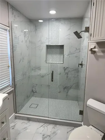 Bathroom with marble finish flooring, a marble finish shower, recessed lighting, and vanity