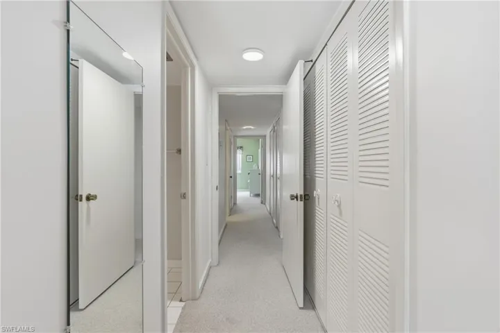 Corridor featuring light colored carpet and baseboards