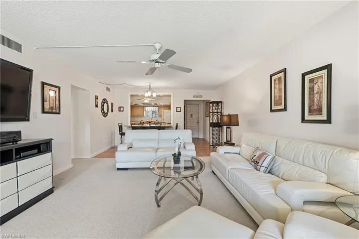 Living area featuring a textured ceiling, carpet flooring, and ceiling fan