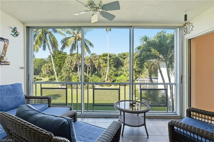 Sunroom featuring tile patterned flooring, view of scattered trees, and a textured ceiling