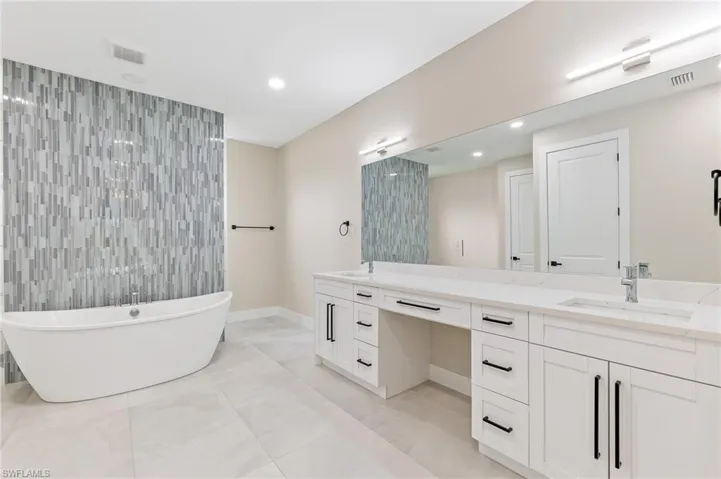 Bathroom with a soaking tub, double vanity, and recessed lighting