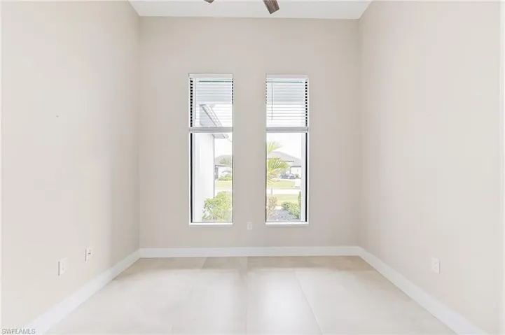 Unfurnished room with ceiling fan and baseboards