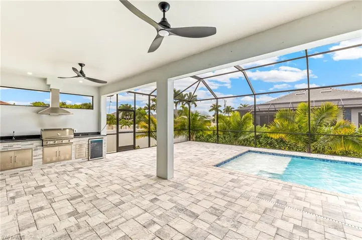 View of patio featuring a ceiling fan, beverage cooler, an outdoor pool, a sunroom, and a lanai