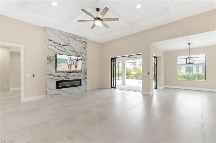 Unfurnished living room featuring ceiling fan, a fireplace, coffered ceiling, and beamed ceiling