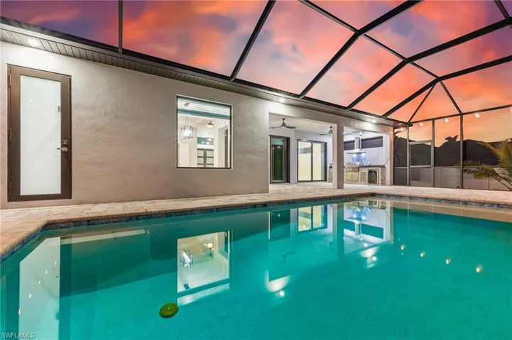 Pool at dusk with a sunroom, an outdoor pool, a lanai, and a patio