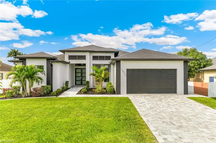 Prairie-style home featuring decorative driveway, stucco siding, a front yard, and a garage