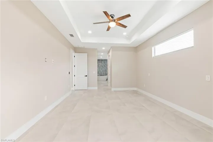 Spare room featuring a raised ceiling, a ceiling fan, and recessed lighting