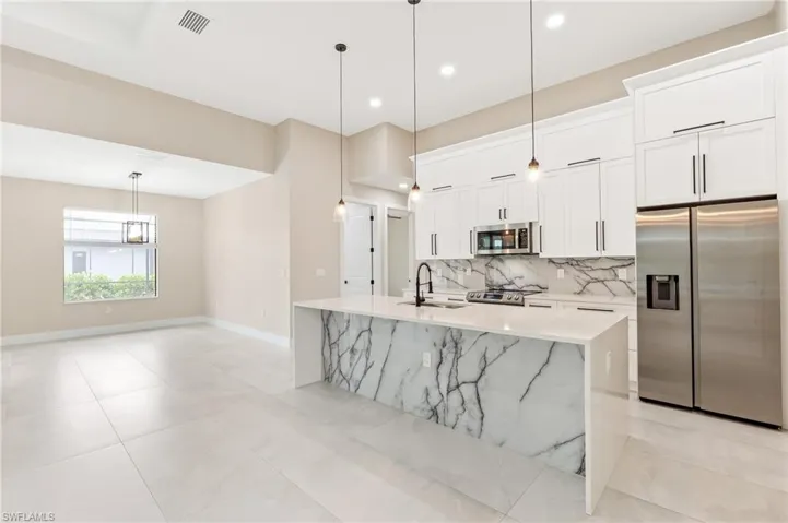 Kitchen featuring appliances with stainless steel finishes, decorative light fixtures, tasteful backsplash, white cabinets, and recessed lighting