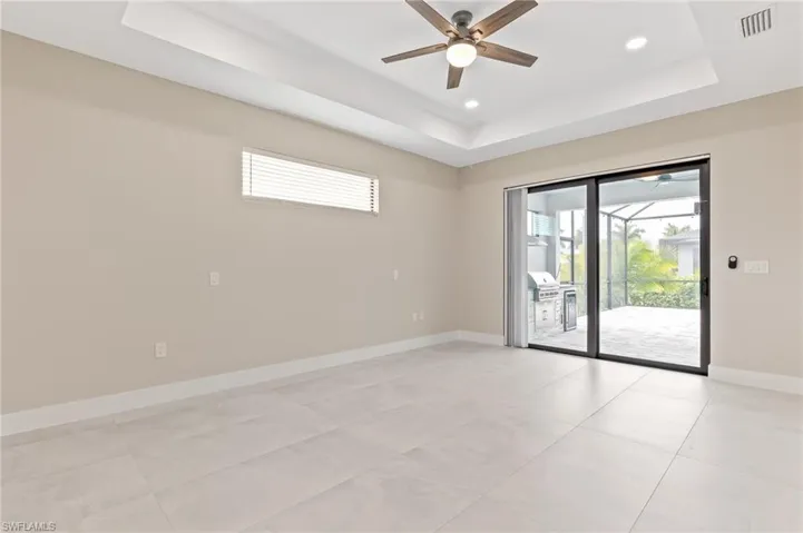 Unfurnished room with a tray ceiling, plenty of natural light, a ceiling fan, and recessed lighting