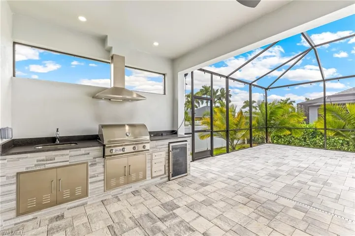 View of patio / terrace with a sunroom, a lanai, beverage cooler, exterior kitchen, and ceiling fan