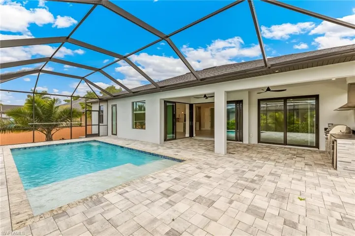 Swimming pool with a sunroom, glass enclosure, a patio, and area for grilling