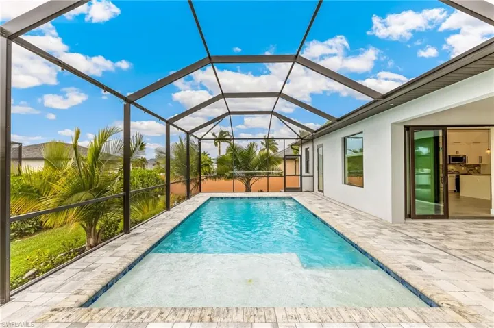 Swimming pool featuring a sunroom, glass enclosure, and a patio area