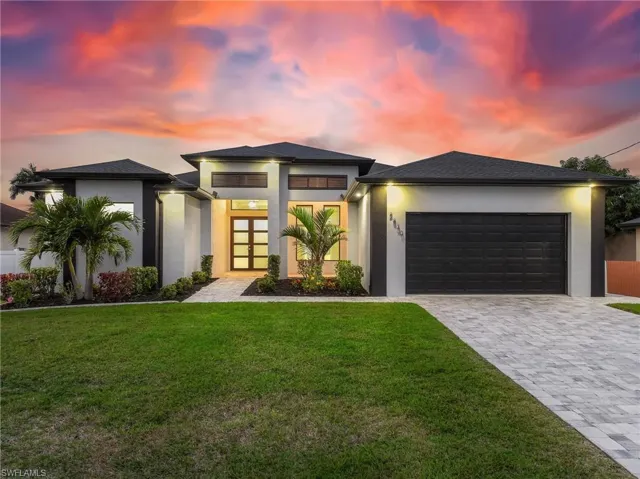 Prairie-style home featuring decorative driveway, an attached garage, a yard, and stucco siding