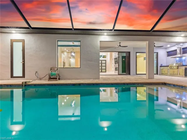 Rear view of house featuring a ceiling fan, exterior kitchen, an outdoor pool, and a lanai