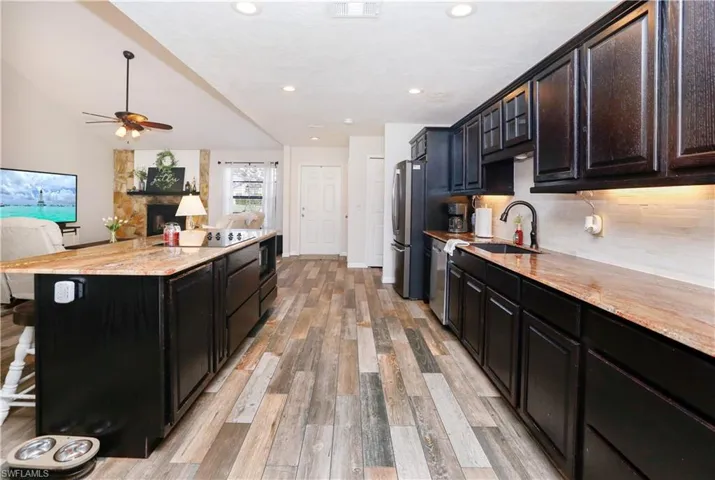 Kitchen with a kitchen bar, sink, stainless steel appliances, a fireplace, and light hardwood / wood-style floors
